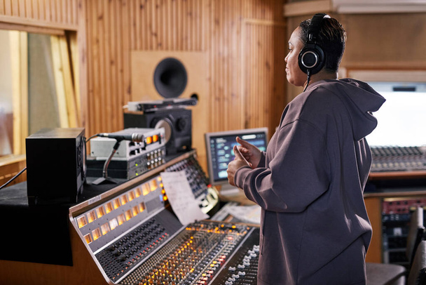 Side view portrait of female music producer showing thumbs up while supporting band in recording studio, copy space - Photo, Image