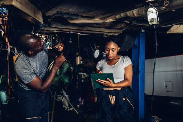 Professional Car Mechanic is Investigating Under a Vehicle on a Lift in Service. Auto Service Worker Checking Car Under Carriage Look For Issues. Car service technician check and repair customer car. - Foto, Imagem