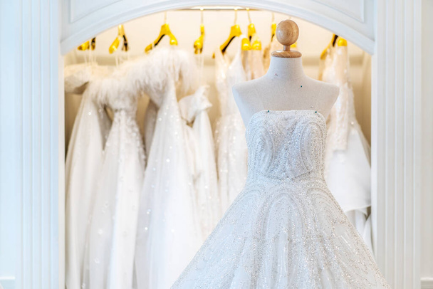 Wunderschöne Brautkleider, Brautkleider, die an Kleiderbügeln hängen und Schaufensterpuppen im Atelier. Mode-Look. - Foto, Bild