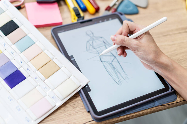 Hand Fashion ontwerper vrouw tekent schetsen voor een nieuw mode-ontwerp, maakt gebruik van een elektronische tablet modieuze kleding. Close up actief werkende vrouwelijke werkruimte - Foto, afbeelding