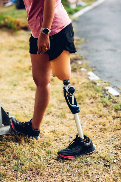 Athlete with prosthetic leg doing warm up exercise on park. Woman wearing prosthetic equipment for jogging. Female with prosthesis of leg - Foto, Imagem