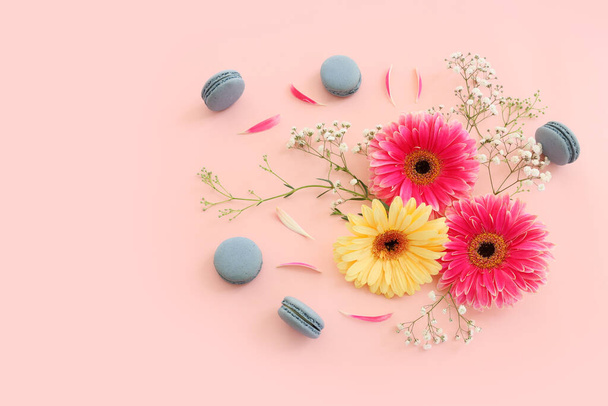 Top view of blue macaron or macaroon and flowers over pastel pink background. Flat lay - Photo, image