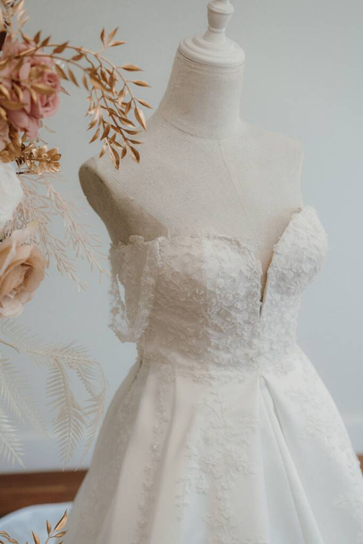A vertical closeup shot of a lace wedding dress on a mannequin - Φωτογραφία, εικόνα