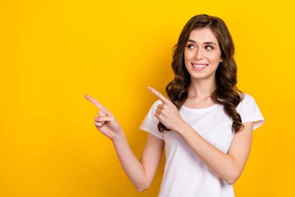 Photo of young pretty woman promoter curly brown hairdo looking empty space indicate fingers useful tips isolated on yellow color background. - Foto, Imagen