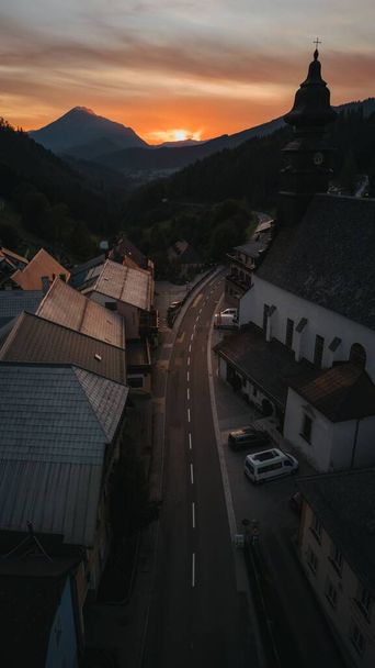 A drone vertical shot of a small road in a rural village in the Austrian mountains during sunset - Photo, Image