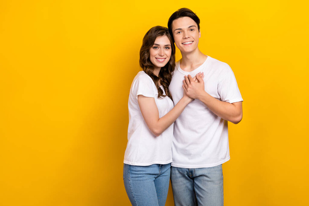 Photo of positive charming couple wear white t-shirts hugging empty space isolated yellow color background. - Fotoğraf, Görsel