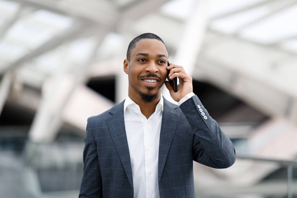 Κλήση κινητού. Πορτρέτο του Νέου Μαύρου Επιχειρηματίας Μιλώντας στο κινητό τηλέφωνο στο αεροδρόμιο, Όμορφος Χαμογελώντας Αφροαμερικανός Άνδρας φορώντας κοστούμι Απολαμβάνοντας ευχάριστη τηλεφωνική συνομιλία μετά την άφιξη, Αντιγραφή χώρου - Φωτογραφία, εικόνα