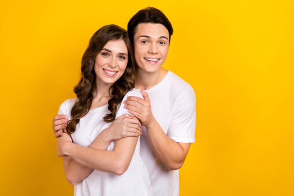 Photo of dreamy adorable couple wear white t-shirts embracing empty space isolated yellow color background. - Fotoğraf, Görsel