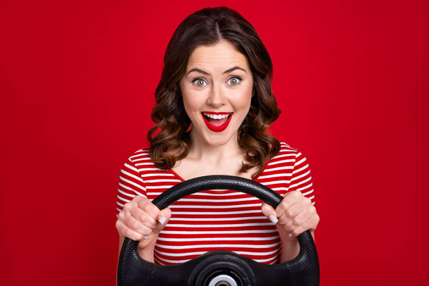 Photo of adorable lady driver controlling car steering wheel come to meet friends wear striped top isolated red color background. - 写真・画像