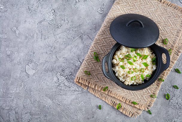 Stewed rice with chicken in a pot on grey background. Top view - Photo, image