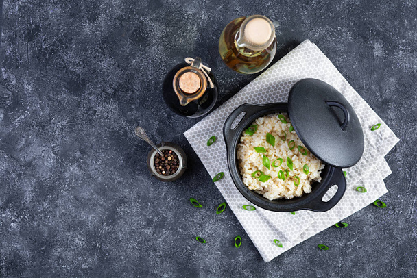 Stewed rice with chicken in a pot on dark grey background. Top view - Foto, Imagen