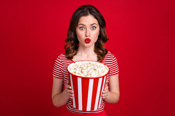 Photo of flirty kissing lady watch soap opera drama movie hold big popcorn bucket wear striped top isolated red color background. - Фото, изображение