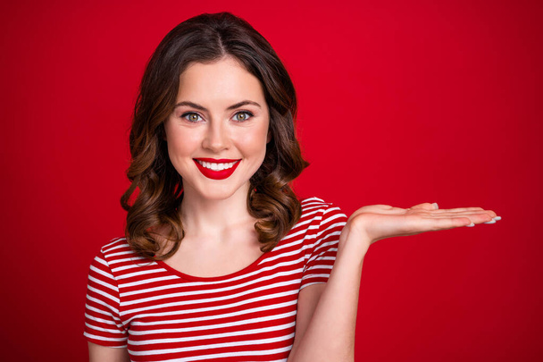 Portrait of positive pretty girl toothy smile arm hold empty space special offer low price procedure isolated on red color background. - Photo, image