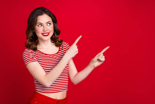 Portrait of gorgeous cheerful girl look direct fingers empty space proposition isolated on red color background. - Valokuva, kuva