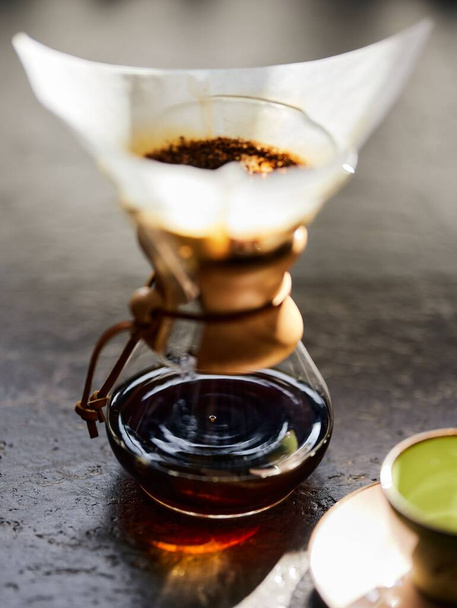 A vertical closeup shot of coffee dripping through a paper filter over a cup - Foto, imagen