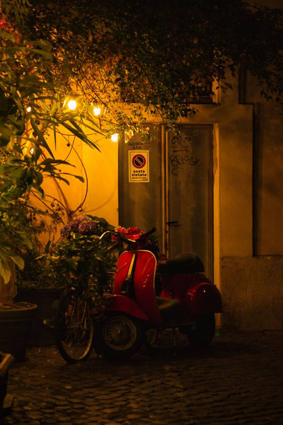 A vertical shot of a classic red Italian scooter at night - Foto, immagini