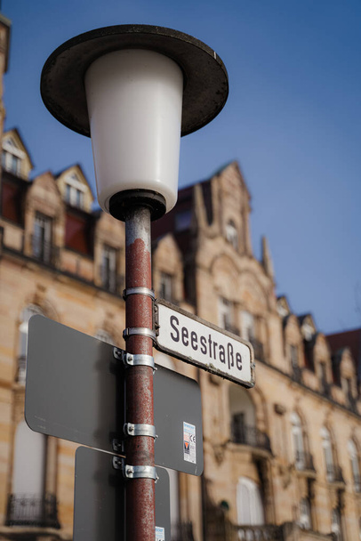 A vertical shot of a street light and sign with buildings in the background on Seestrasse in Constance - Foto, Imagen