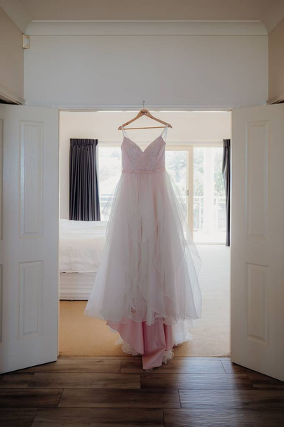 A vertical shot of a bride's dress on a hanger - Zdjęcie, obraz