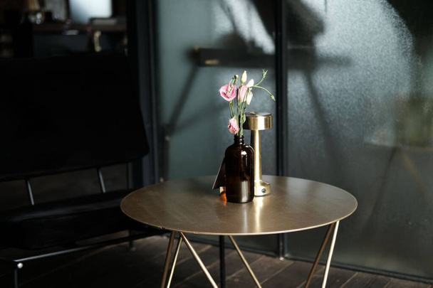 a vase of pink flowers on a coffee table - Fotoğraf, Görsel