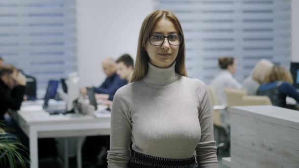Irodai munkás portréja, aki a modern irodai kamerát nézi, női alkalmazott elégedett a jó munkalehetőséggel, közeli portré lassított felvételen - Felvétel, videó