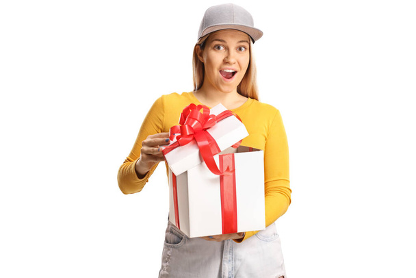 Ενθουσιασμένη περιστασιακή νεαρή γυναίκα που ανοίγει ένα κουτί δώρου και κοιτάζει την κάμερα απομονωμένη σε λευκό φόντο - Φωτογραφία, εικόνα