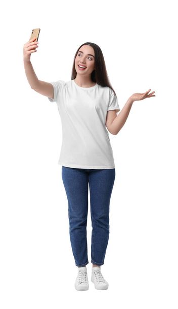 Smiling young woman taking selfie with smartphone on white background - Foto, imagen