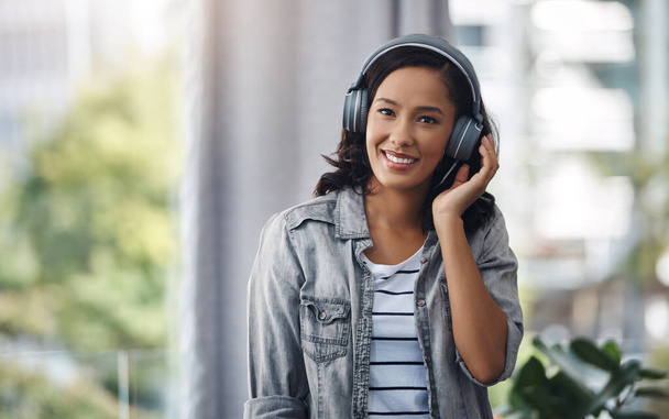 I could recommend tons of new music to you. Portrait of a young woman wearing headphones while listening to music at home - Zdjęcie, obraz