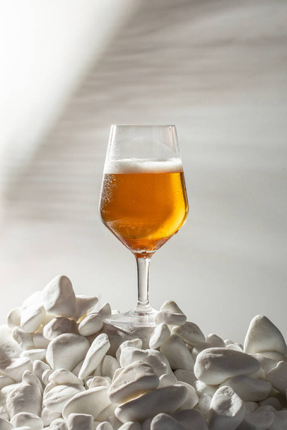 Close-up ποτήρι κρύα μπύρα με αφρό και σταγόνες νερού με φυσική σκιά παλάμη, - Φωτογραφία, εικόνα