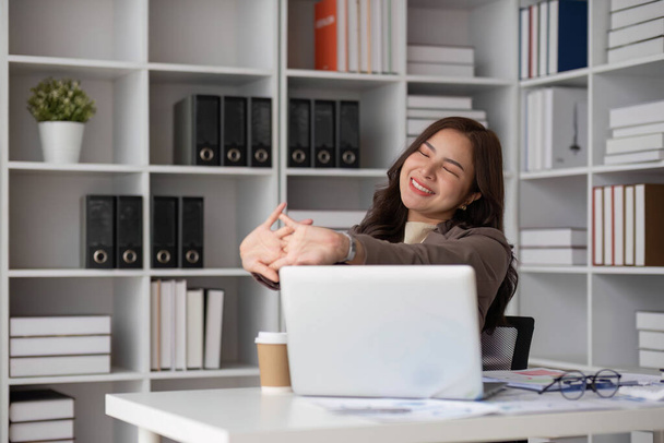 Las mujeres de negocios o la mujer trabajadora se estiran o perezosamente para relajarse en su escritorio mientras hace su trabajo en la oficina... - Foto, Imagen