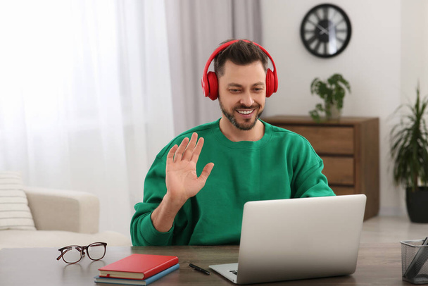 Man in headphones studying on laptop at home. Online translation course - Foto, immagini