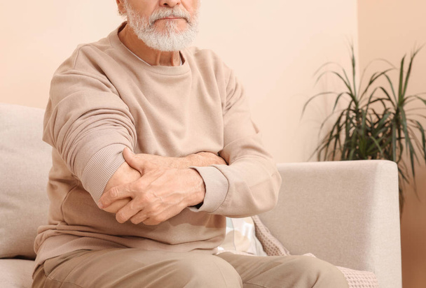 Senior man suffering from pain in his hand at home, closeup. Arthritis symptoms - 写真・画像