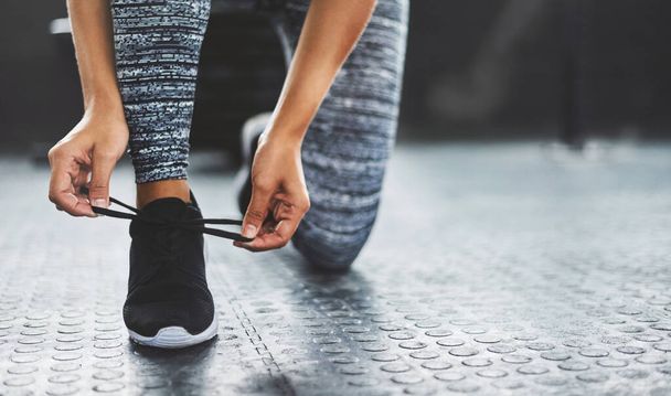 Be the best you can be. a woman tying her shoelaces in a gym - 写真・画像