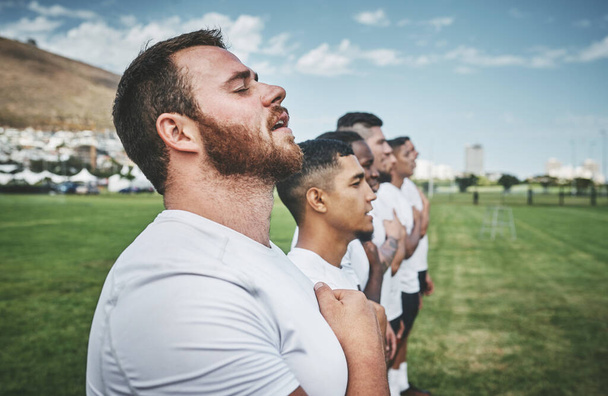Eine große Tradition. ein Team selbstbewusster junger Rugbyspieler, die vor einem Rugbyspiel auf einem Feld stehen und ihre Hymne singen - Foto, Bild