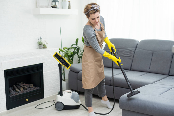 Canapé de nettoyage femme avec aspirateur à la maison
. - Photo, image