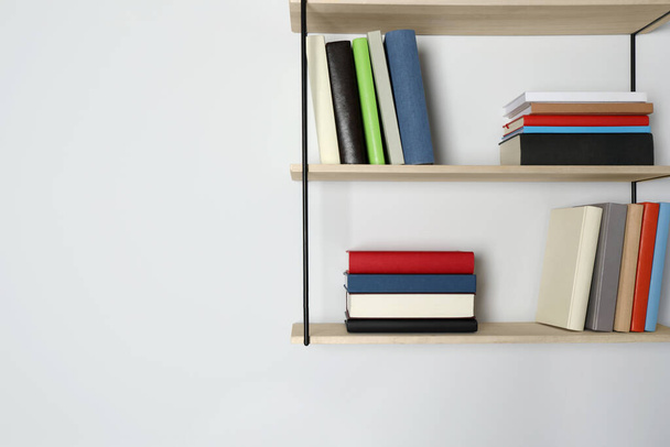 Shelves with many hardcover books on white wall. Space for text - Photo, image