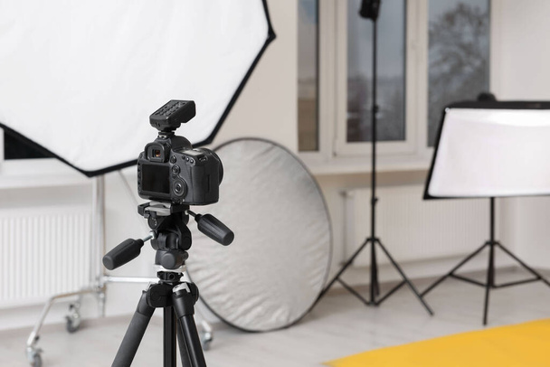 Camera on tripod and professional lighting equipment in modern photo studio, space for text - Foto, immagini