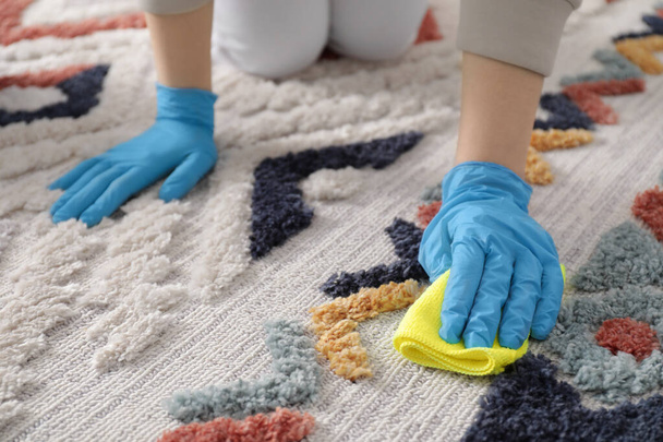 Woman in rubber gloves cleaning carpet with rag indoors, closeup - Foto, Imagen