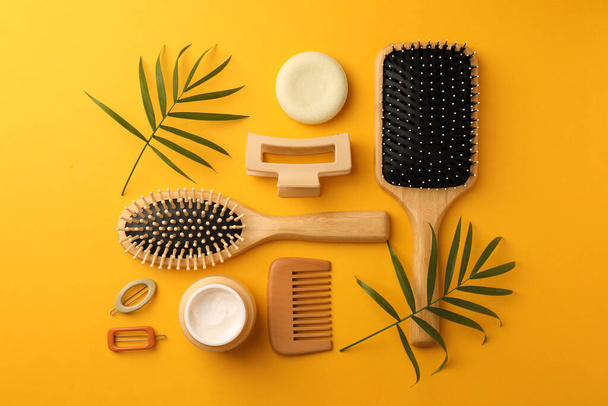 Flat lay composition with wooden brushes and different hair products on orange background - Fotografie, Obrázek