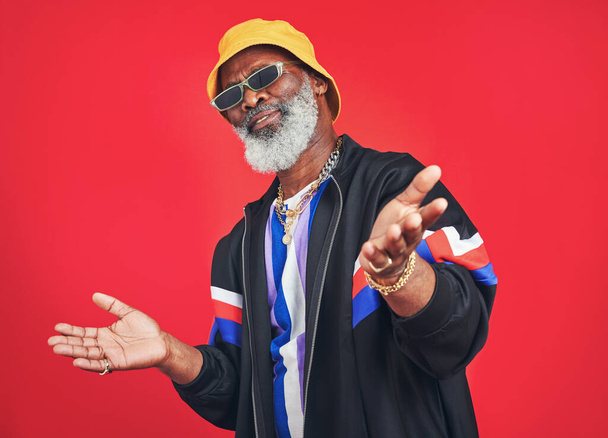 I wont mind giving you some vintage fashion tips. Studio shot of a senior man wearing retro attire while posing against a red background - Fotó, kép