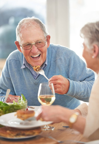 Šťastný, milující a starší pár spolu obědvají v jídelně svého moderního domova. Štěstí, úsměv a starší muž a žena v důchodu mluvit, sblížení a těší jídlo v jejich domě. - Fotografie, Obrázek
