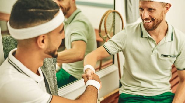 The social side of sport. two young men shaking hands in the locker room after a game of squash - Foto, Imagem