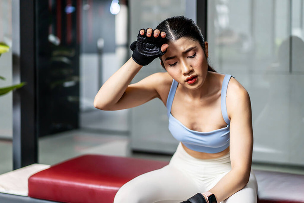 Portrait young asian woman in gym after workout, tired have sweaty and shortness of breath after physical training or exercise to burn energy, build muscle strength on training class in fitness. - Foto, immagini