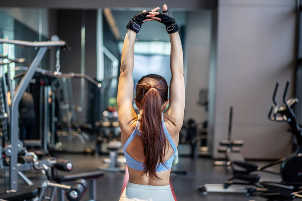 Jovem mulher asiática ativa esticando seu corpo aquecido antes do treino intenso no ginásio, exercícios básicos de ginástica realizados pela jovem mulher - Foto, Imagem