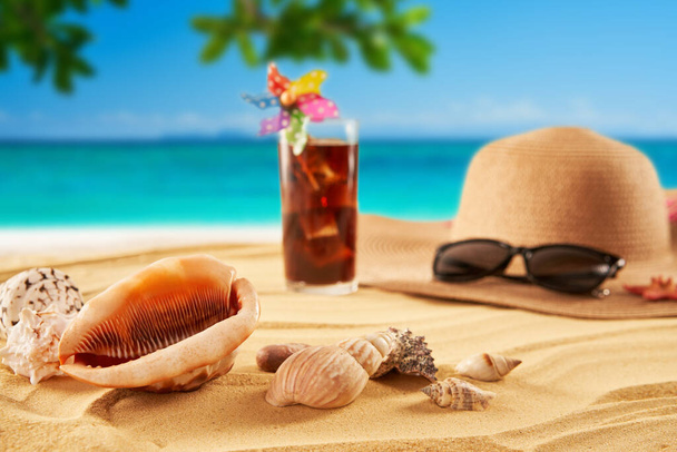 Relax on the beach. Summer time vacation concept. Straw hat, sunglasses and cocktail on the sand and sea background. Travel - Fotó, kép