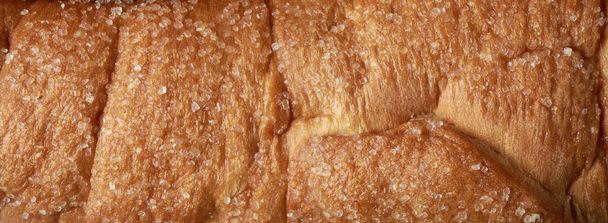panoramic view of surface of freshly baked sweet sugar coated bun, sprinkled sugar and toning, full frame food background taken straight from above - Foto, afbeelding