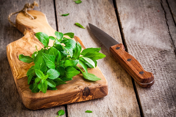 bunch of fresh organic basil in olive cutting board with knife - Photo, image