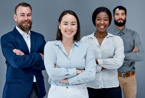 効果的なチームワークは、当社に多くの利点をもたらします。灰色の背景を背景に一緒に立っているビジネスマンのグループの肖像画 - 写真・画像