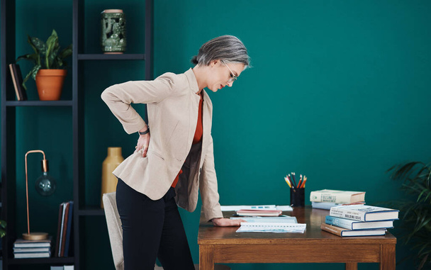 Ouch My back. an attractive mature businesswoman standing and suffering from backache while in her home office - Φωτογραφία, εικόνα
