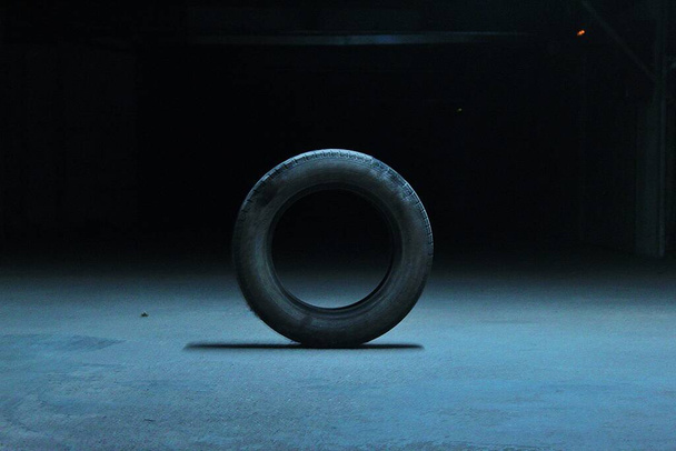 A car tire in the ground on a dark background - Fotoğraf, Görsel
