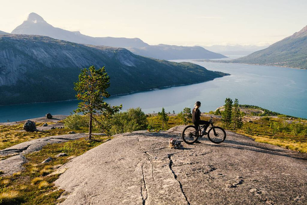 A beautiful view of a cyclist enjoying the view of a river and mountains. - Foto, afbeelding